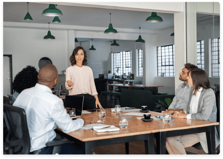 
                    Female leader presenting to attentive colleagues during a meeting in a modern workspace,
                    symbolizing kept.pro's collaborative and integrated partnership approach with client companies.
                  