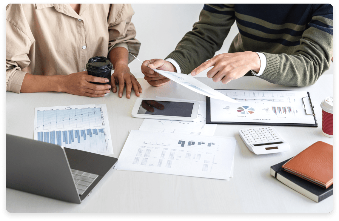 
                  Two professionals analyzing financial reports and KPIs, surrounded by documents,
                  a tablet, a calculator, and laptops on a white table, illustrating the detailed
                  financial oversight provided by kept.pro services.
                