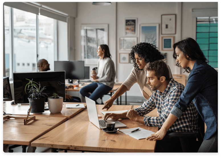 
                  A diverse group of four professionals, including two women and two men,
                  are engaged in a discussion over a laptop in a modern office setting,
                  symbolizing collaboration and expertise in a tech company environment.
                